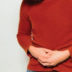 A woman holding her abdomen. There are many types of harmful organisms that can negatively affect your health