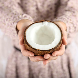 A woman holding a halved coconut shell.